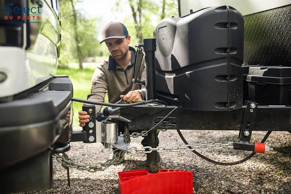 Man attaching a hitch to a trailer with a focus on safety and preparation.