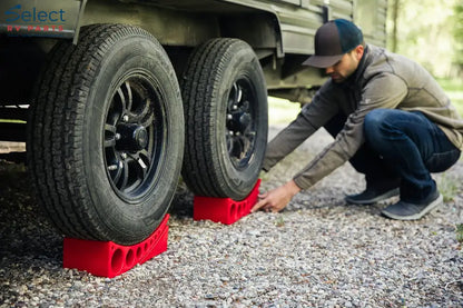 Person changing a tire on a vehicle using red tire changers.