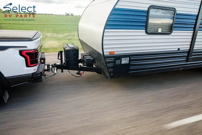 Truck towing a small camper on a road with green fields in the background